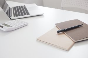 sporządzanie operatu szacunkowego na laptopie, na biurku dokumenty do wyceny nieruchomości